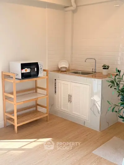 Charming kitchenette with modern sink and microwave, perfect for compact living spaces.
