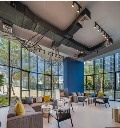 Modern living room with large windows and stylish decor in a luxury apartment building.