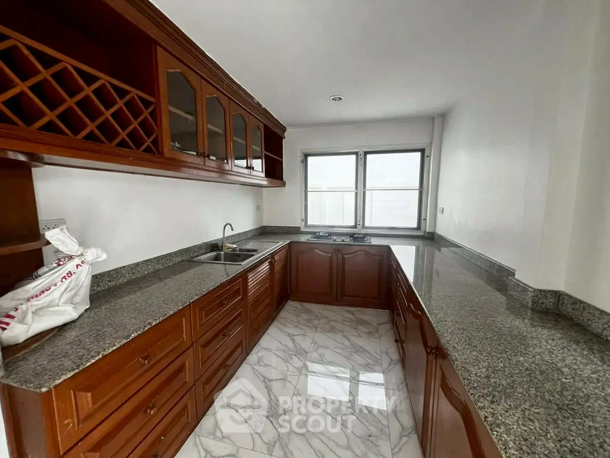 Elegant kitchen with granite countertops and wooden cabinetry, featuring a gas stove and ample natural light.