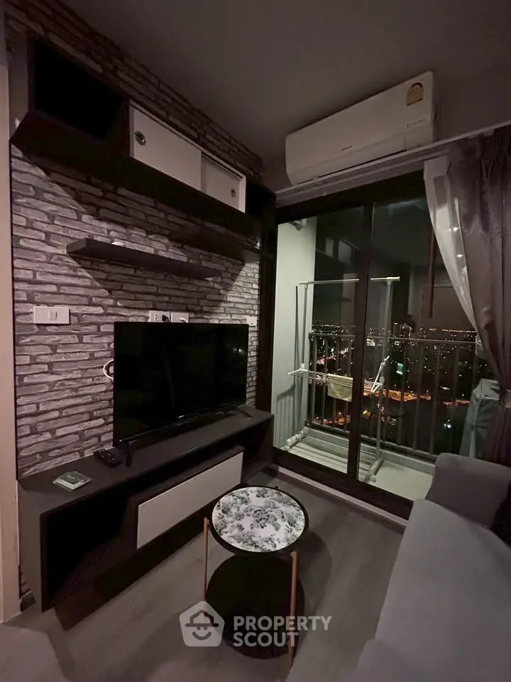 Modern living room with city view, featuring sleek TV setup and cozy balcony access.