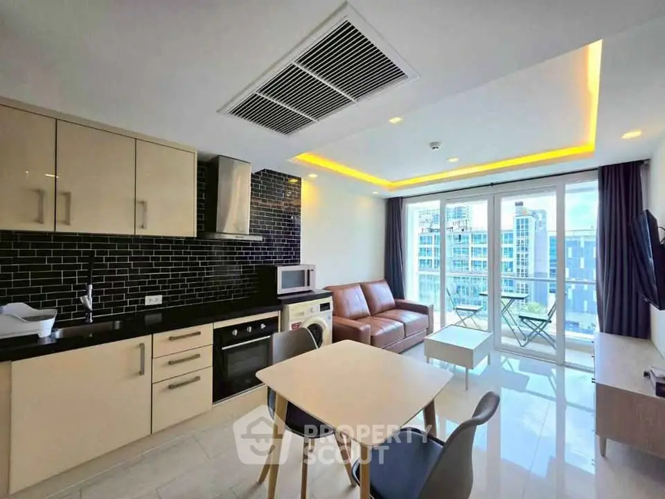 Modern open-plan living room with kitchen, featuring sleek design and city view balcony.