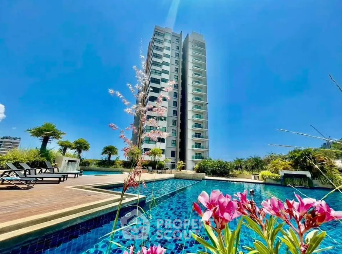 Luxurious high-rise building with stunning pool and lush garden under clear blue sky.