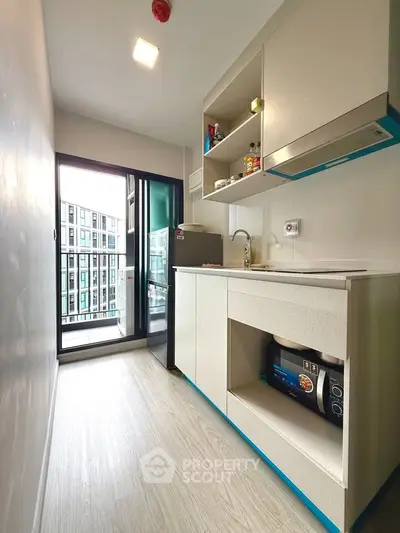 Modern compact kitchen with sleek cabinetry and balcony view in urban apartment