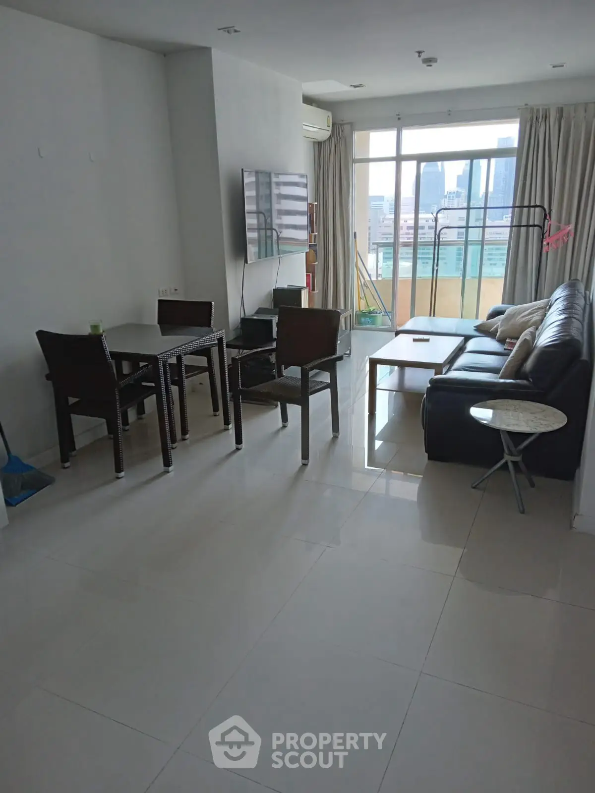 Spacious living room with modern furniture and city view balcony.