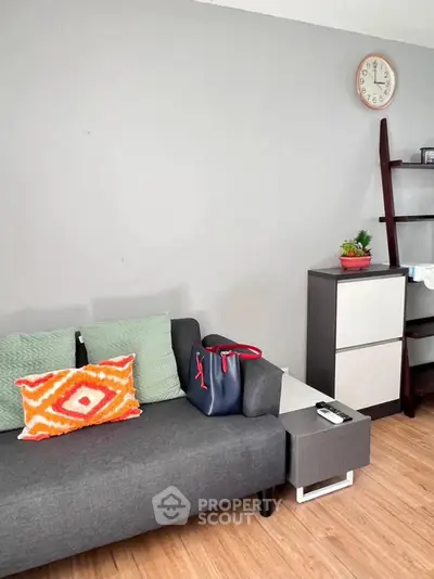 Modern living room with stylish sofa, vibrant cushions, and sleek shelving unit.