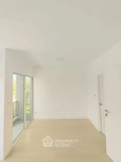 Bright empty room with large sliding glass doors leading to a balcony, showcasing modern minimalist design.