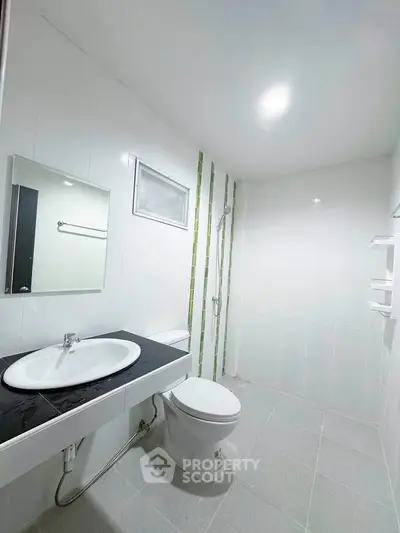 Modern bathroom with sleek design and white tiles, featuring a shower and vanity sink.