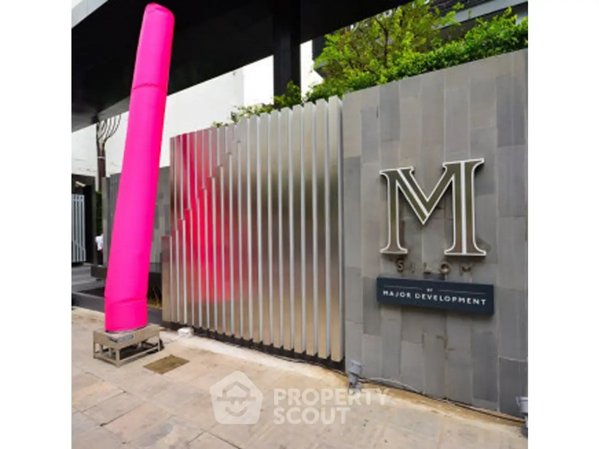 Modern building entrance with sleek design and prominent M logo, showcasing urban sophistication.