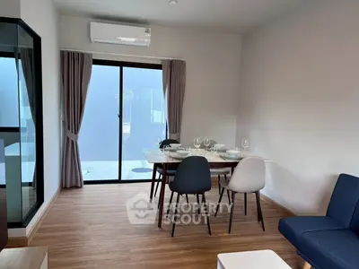 Modern dining area with stylish furniture and large glass doors leading to a balcony, perfect for entertaining.