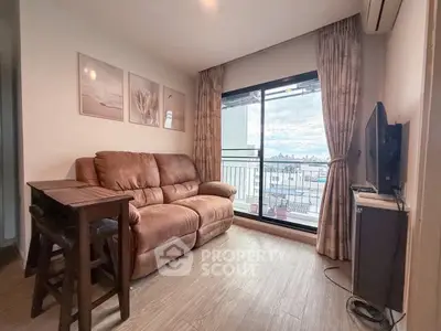 Cozy living room with large window and city view, featuring a comfortable sofa and modern decor.