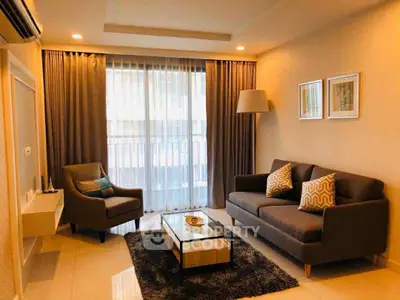 Modern living room with cozy seating and elegant decor, featuring large windows and ambient lighting.