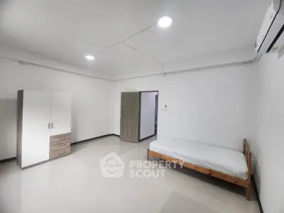 Spacious minimalist bedroom with single bed and wardrobe, ideal for modern living.