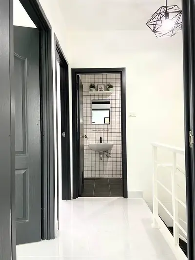 Modern hallway leading to a stylish bathroom with geometric lighting and tiled walls.