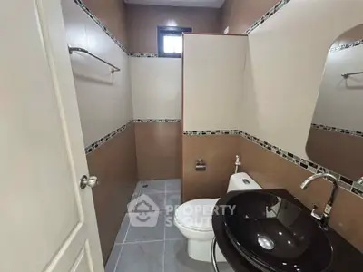 Modern bathroom with sleek black sink and tiled walls, featuring a compact yet stylish design.