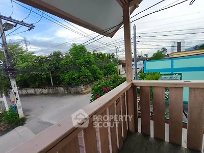 Charming wooden balcony with lush green view in a serene neighborhood.