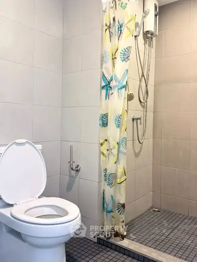 Modern bathroom with shower and toilet featuring a stylish curtain.