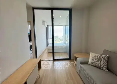 Modern living room with sliding glass door leading to a bright bedroom with city view.