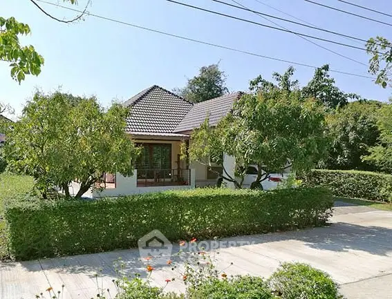Charming single-story house with lush garden and paved driveway in tranquil neighborhood.