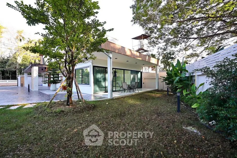 Modern single-story house with large windows and lush garden surroundings.
