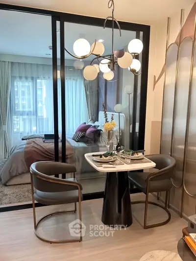 Modern dining area with elegant lighting and view into cozy bedroom through glass partition.