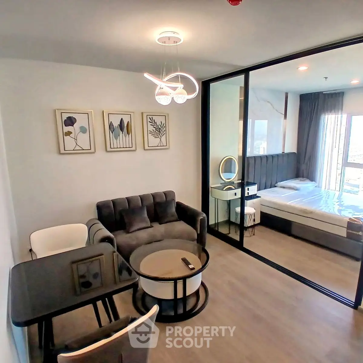 Modern open-plan living room with stylish decor and glass partition to bedroom