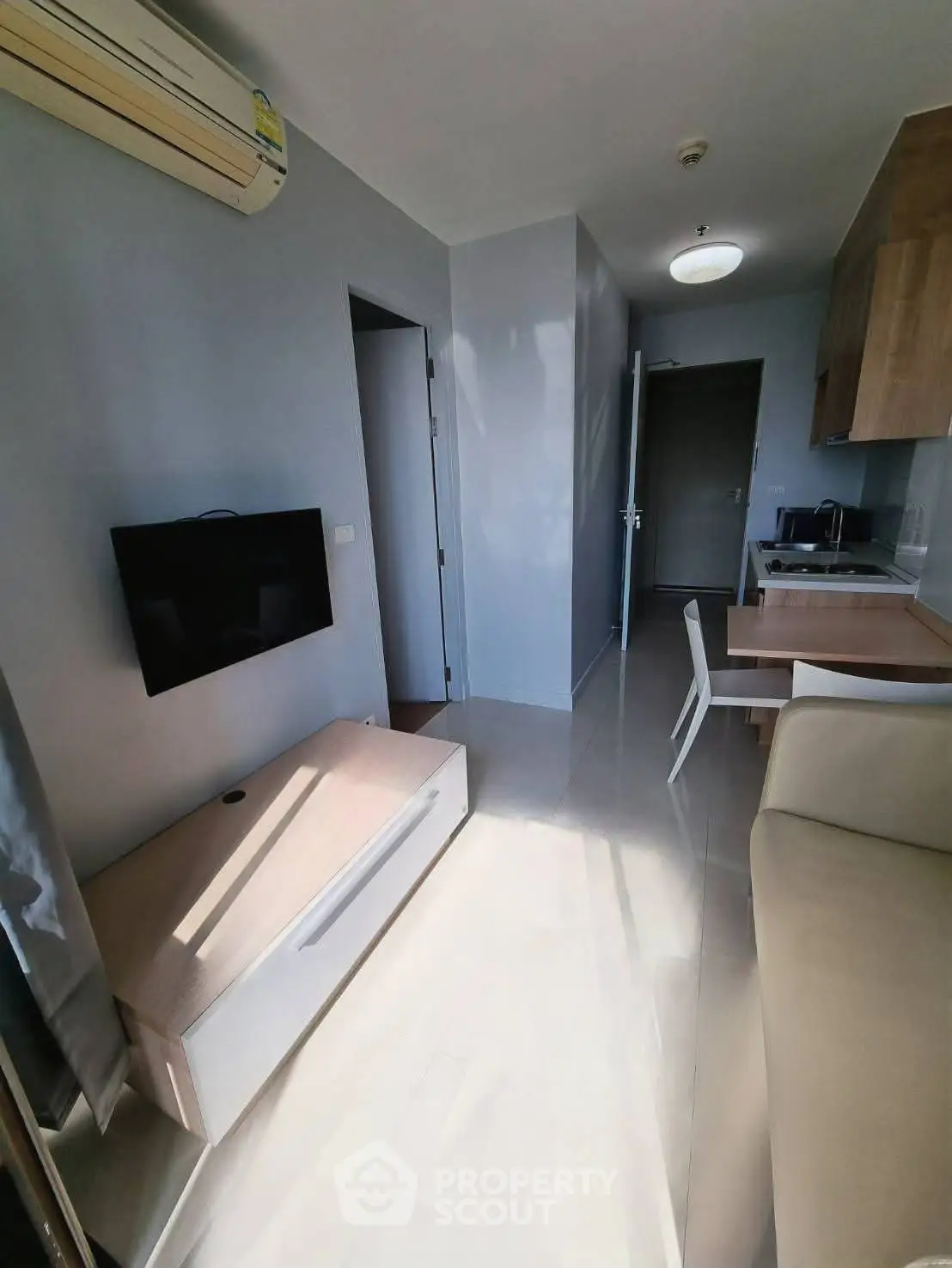 Modern compact living room with wall-mounted TV and sleek kitchen area