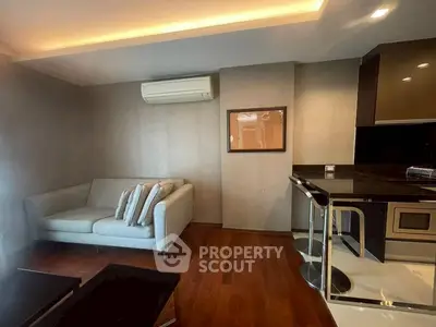 Modern living room with sleek design and cozy sofa, featuring elegant wooden flooring and stylish kitchen area.