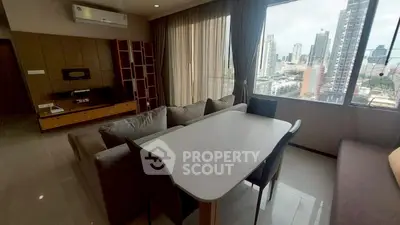 Modern living room with city view, featuring sleek furniture and large windows.
