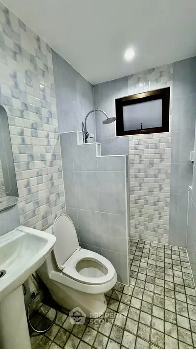 Modern bathroom with tiled walls and floor, featuring a toilet and shower area.
