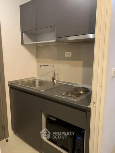 Compact modern kitchen with sleek cabinetry and built-in appliances in a cozy apartment.