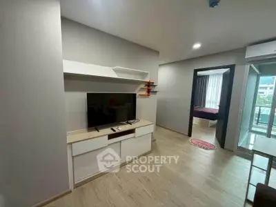 Modern living room with sleek TV unit and view into bedroom and balcony.