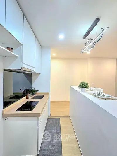 Modern kitchen with sleek design and open layout, featuring stylish lighting and minimalist decor.