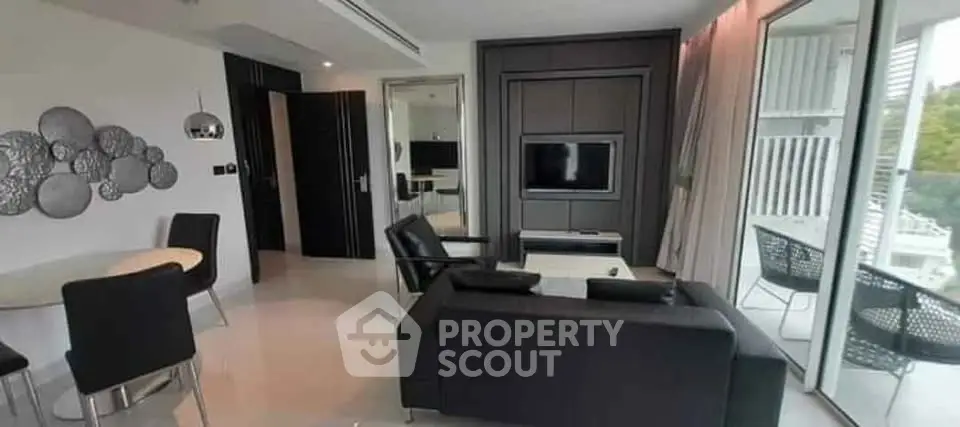 Modern living room with sleek black furniture and large windows offering natural light