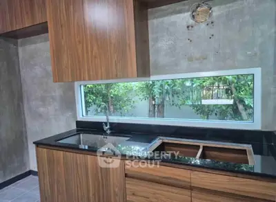 Modern kitchen with sleek wooden cabinets and large window view