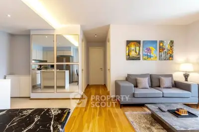 Modern living room with stylish decor and open kitchen layout, featuring a cozy gray sofa and elegant lighting.