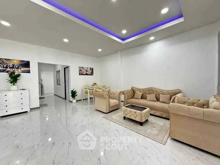 Elegant living room with modern lighting and plush beige sofas on marble flooring.