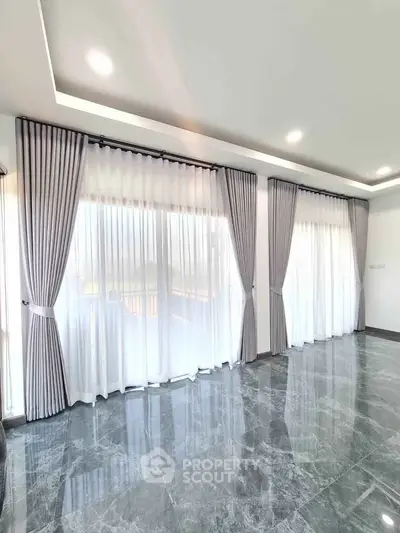 Spacious living room with elegant floor-to-ceiling windows and luxurious marble flooring.