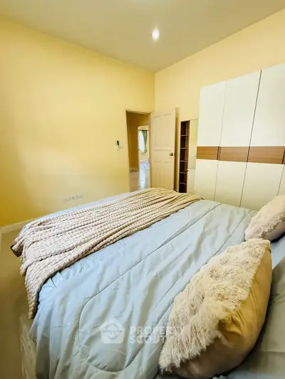 Cozy bedroom with plush bedding and modern wardrobe in a serene setting.
