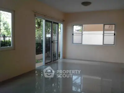 Spacious living room with large windows and sliding glass doors opening to a garden view.
