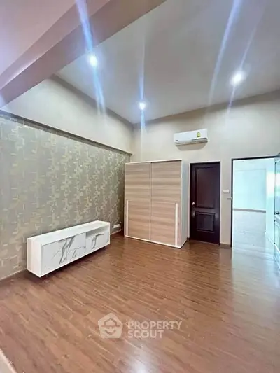 Spacious modern living room with wooden flooring and stylish wallpaper accent wall.
