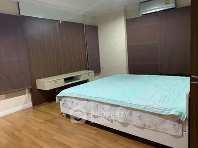 Spacious bedroom with wooden flooring and modern air conditioning unit.