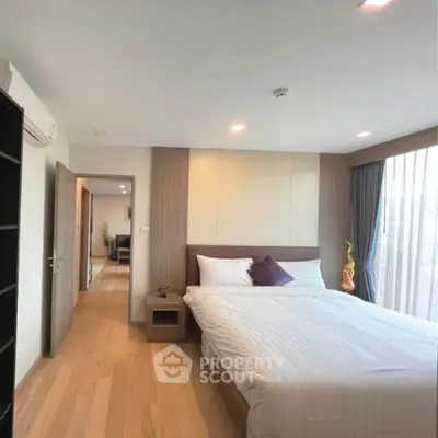 Spacious bedroom with modern decor and natural light in a stylish apartment.