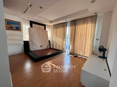 Spacious bedroom with large windows and wooden flooring, perfect for natural light lovers.