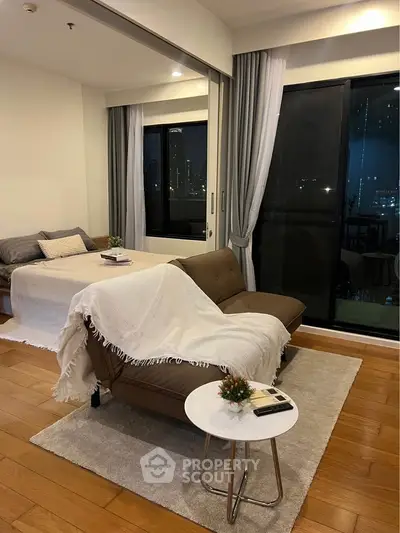Modern studio apartment with cozy living area and city view, featuring stylish decor and natural light.