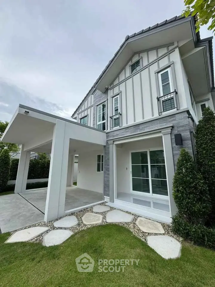 Charming modern house exterior with lush garden and sleek carport design.