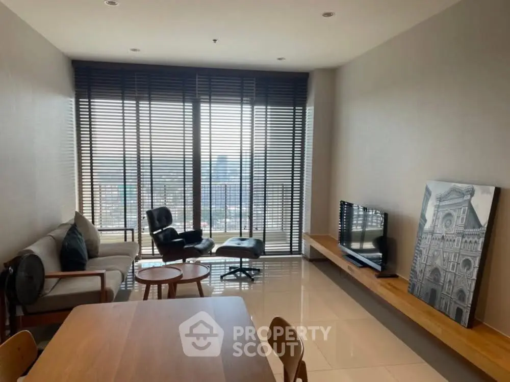 Modern living room with floor-to-ceiling windows and elegant furniture, offering a stunning city view.
