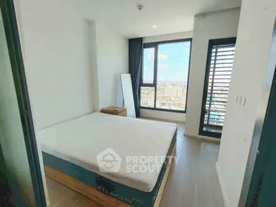 Modern bedroom with large window offering stunning city views in a high-rise apartment.