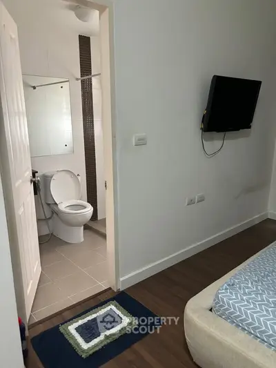 Cozy bedroom with ensuite bathroom featuring modern amenities and wall-mounted TV.