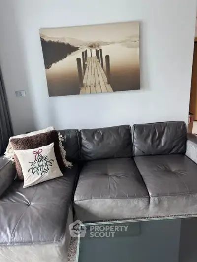Modern living room with stylish gray leather sofa and serene wall art, perfect for relaxation.