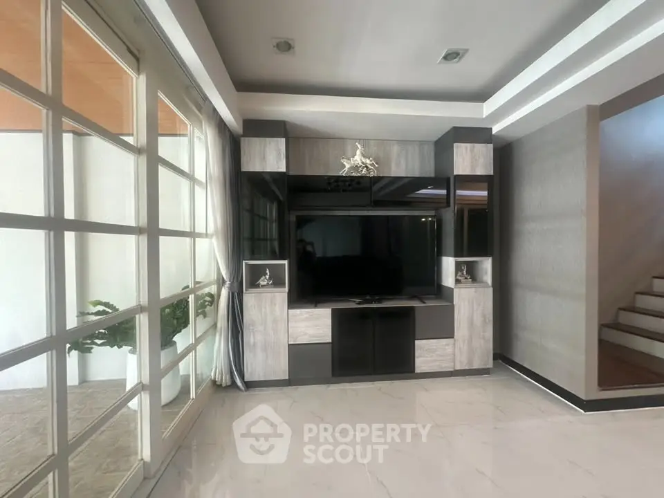 Modern living room with sleek entertainment center and large windows for natural light.
